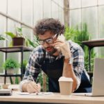Man making business calls in a greenhouse.