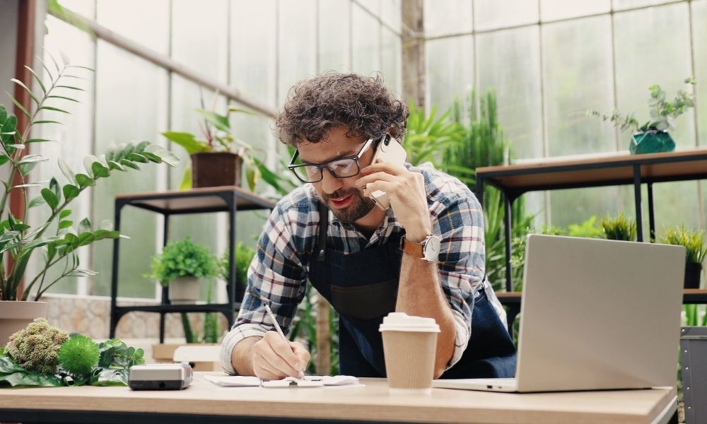 Man making business calls in a greenhouse.