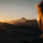 the sun is setting over a mountain range