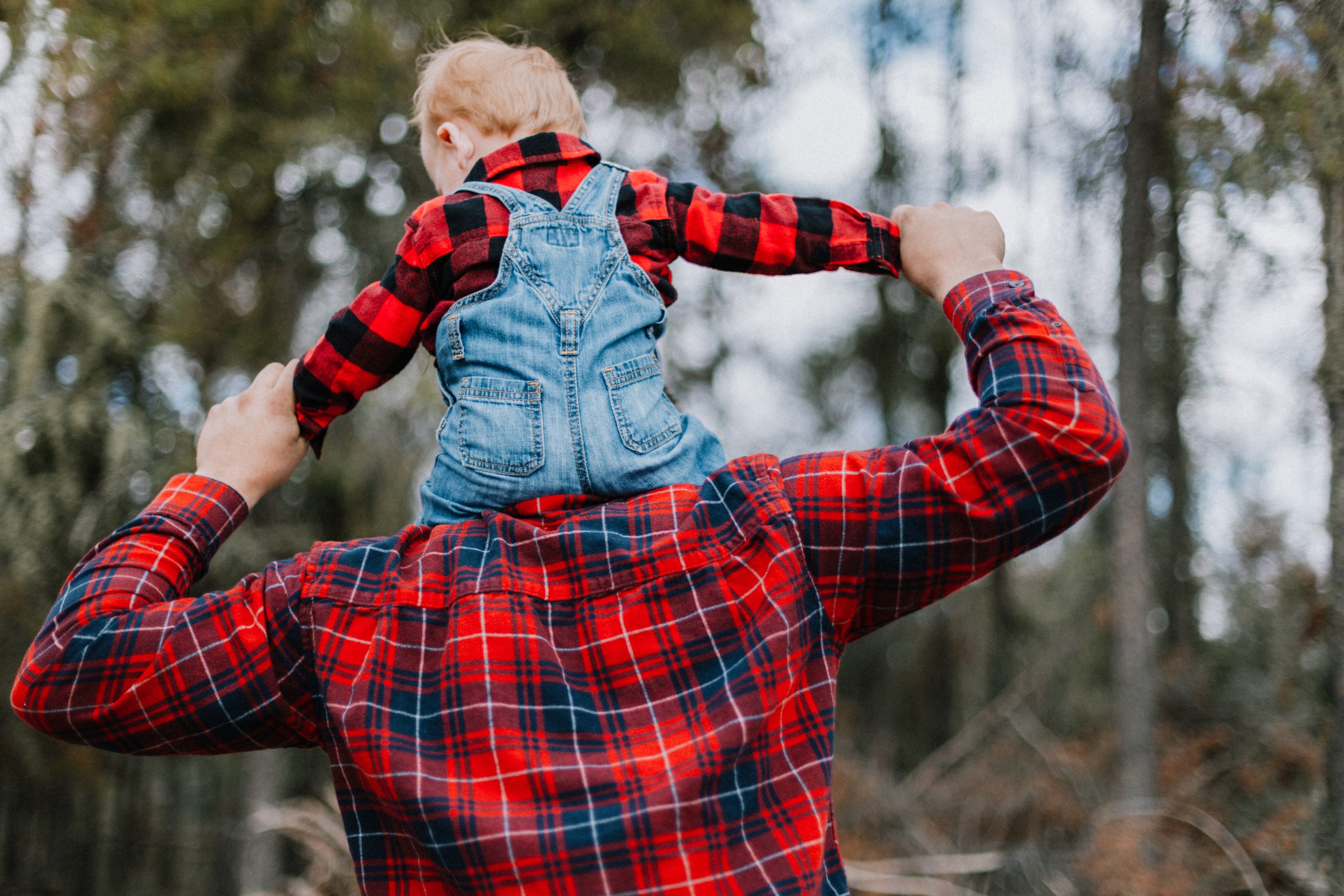 a man holding a child in his arms in the woods